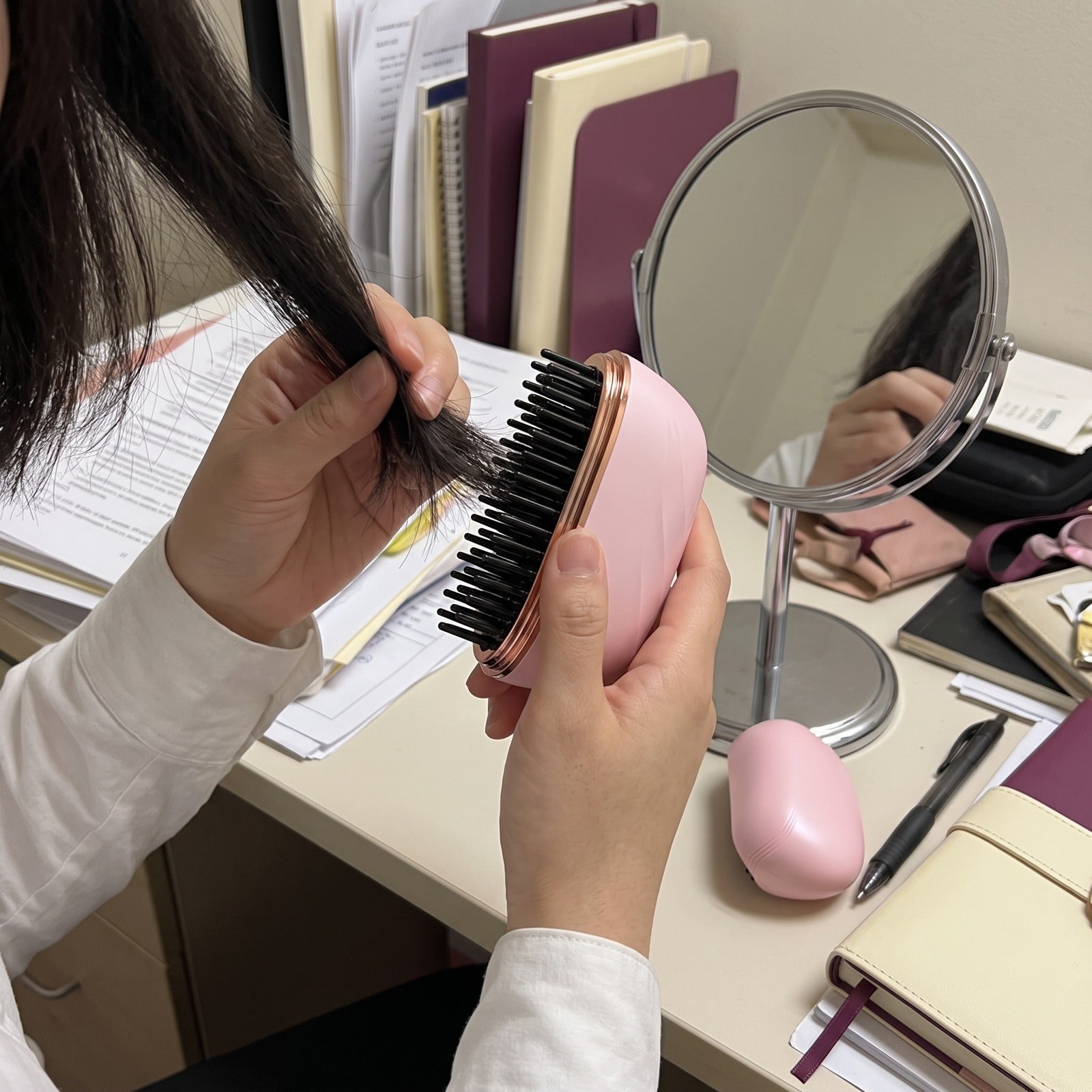 Pink brush dry-hair touch-up at a desk mirror